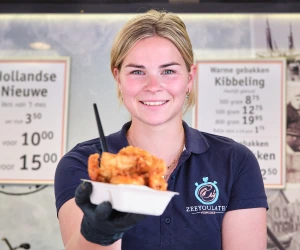 Medewerker van ZeeYouLater Visspecialist met een bakje verse kibbeling in de viskraam in Leusden-Zuid