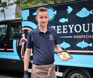 Medewerker van ZeeYouLater Visspecialist met een schaal vis bij de verkoopwagen in Nijkerkerveen