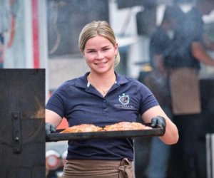 Medewerker van ZeeYouLater Visspecialist met een bakplaat gerookte zalm bij de kraam in Veghel