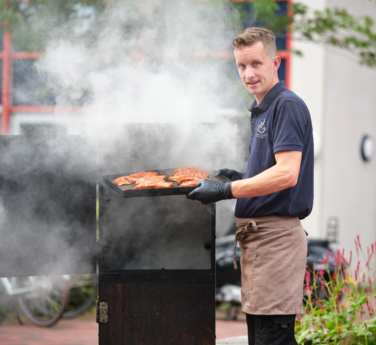 Medewerker van ZeeYouLater Visspecialist haalt versgerookte zalmfilets uit de rookoven