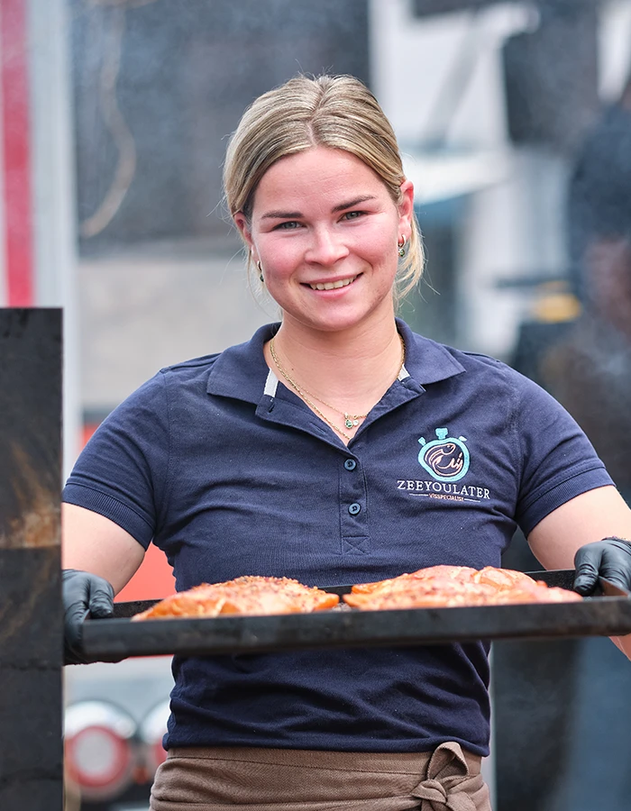 Medewerker van ZeeYouLater Visspecialist met een bakplaat gerookte zalmfilets